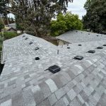 A home with a gray asphalt shingles roof with vents and a skylight.