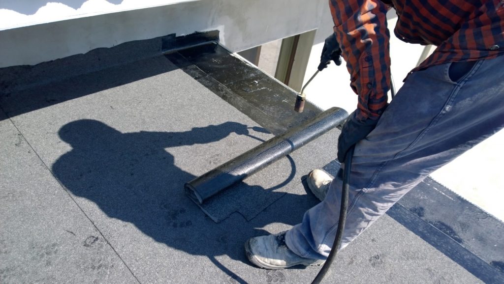 Man installing a flat roof to help illustrate best residential roofing options.